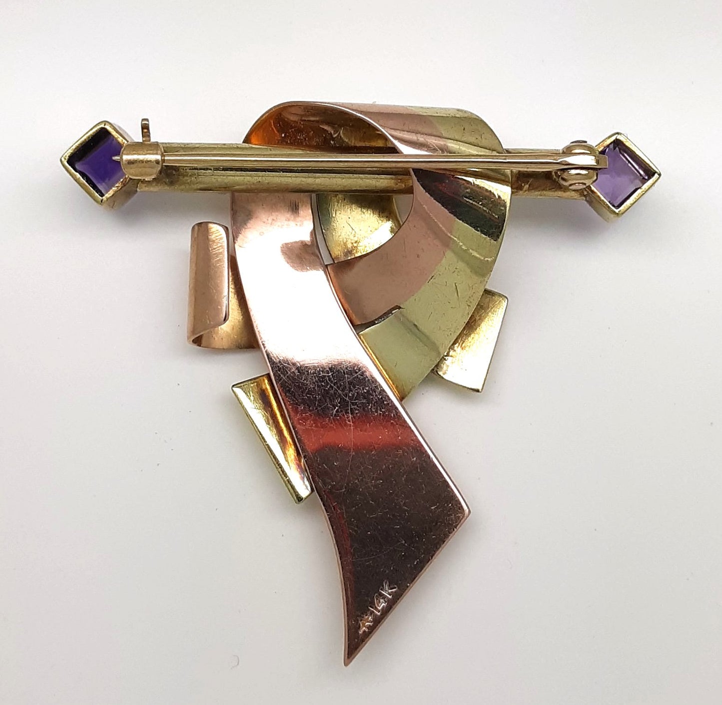 A lady's vintage Retro period 14k green and rose gold ribbon and bar brooch with square baguette cut natural amethyst accents.