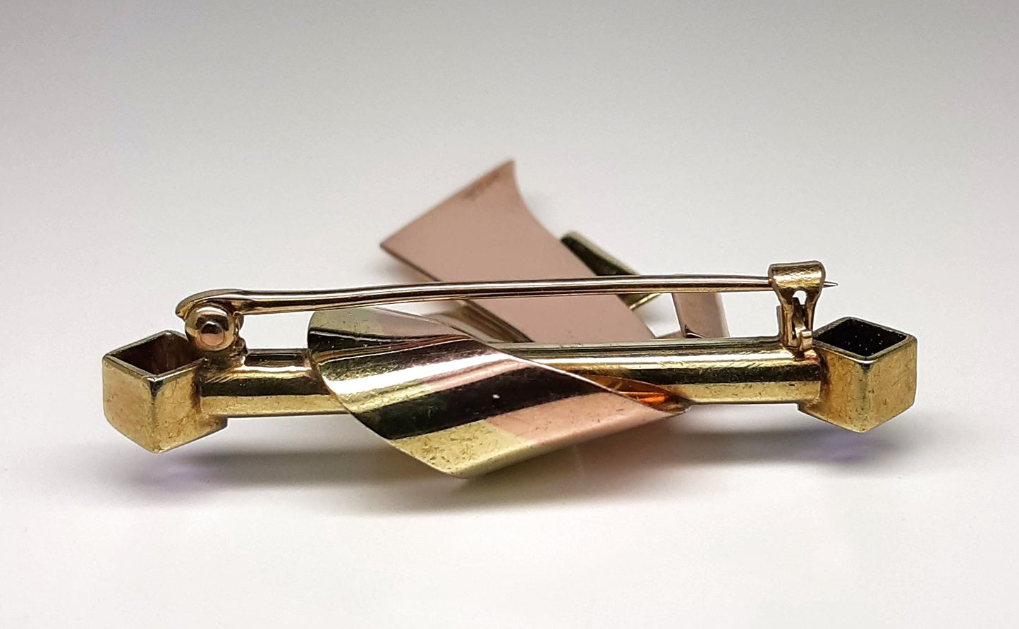 A lady's vintage Retro period 14k green and rose gold ribbon and bar brooch with square baguette cut natural amethyst accents.