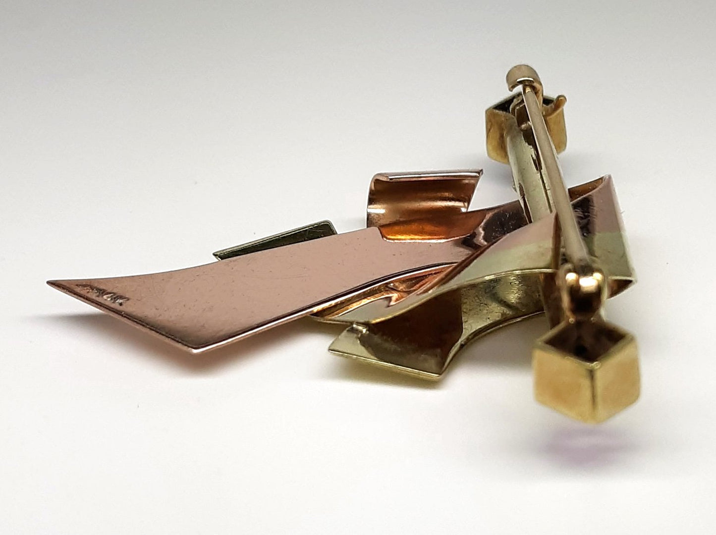 A lady's vintage Retro period 14k green and rose gold ribbon and bar brooch with square baguette cut natural amethyst accents.