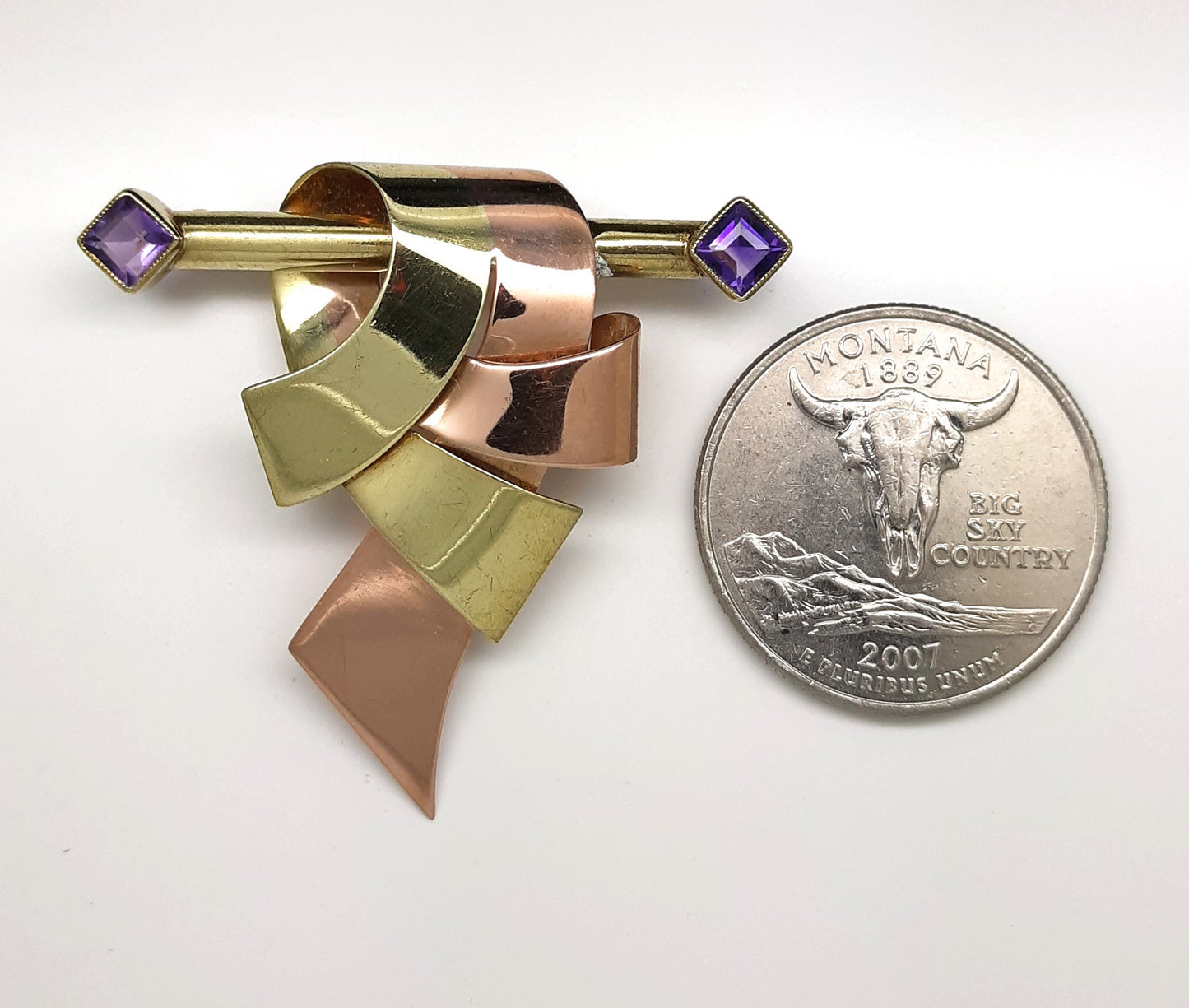 A lady's vintage Retro period 14k green and rose gold ribbon and bar brooch with square baguette cut natural amethyst accents.