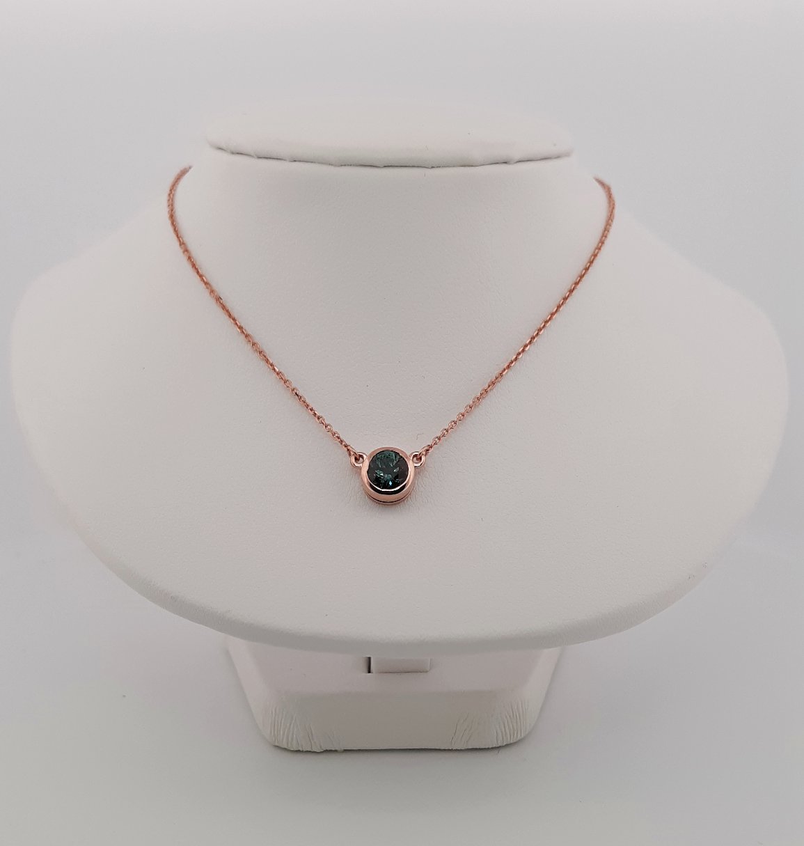 A lady's Minimalist 14k rose gold natural 0.95 carat Montana blue sapphire bezel pendant on chain.