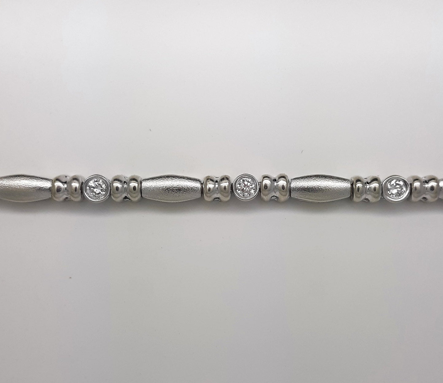 A Lady’s estate 14k white gold diamond accented bead and reel line bracelet.