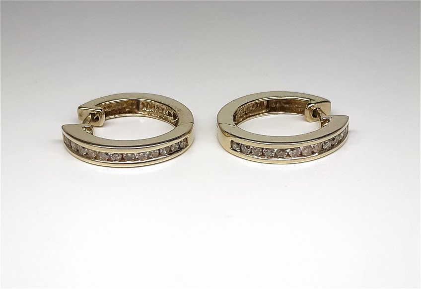 A Lady’s estate pair of 10k yellow gold diamond accented huggie hoop earrings, 0.24ct total weight.