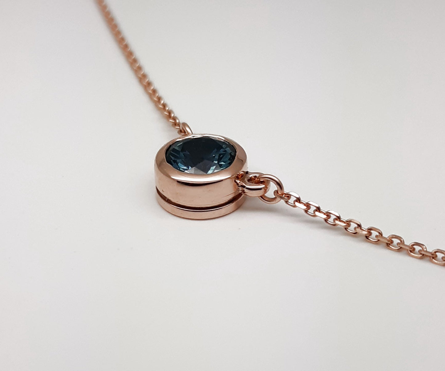 A lady's Minimalist 14k rose gold natural 0.95 carat Montana blue sapphire bezel pendant on chain.