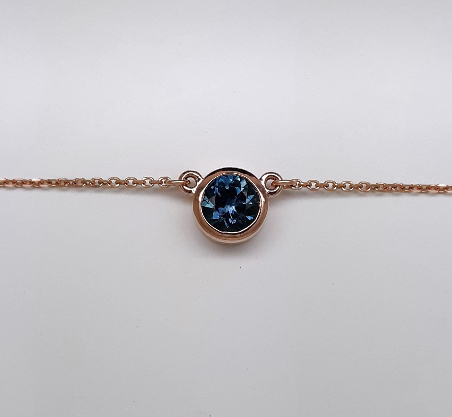 A lady's Minimalist 14k rose gold natural 0.95 carat Montana blue sapphire bezel pendant on chain.